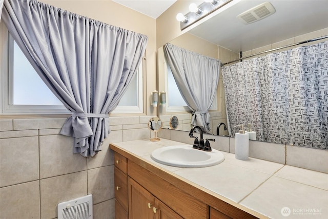 full bath with a shower with curtain, visible vents, tile walls, and vanity