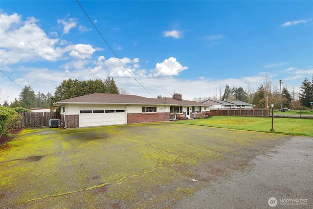 view of front facade with a garage, central AC unit, fence, a front lawn, and brick siding