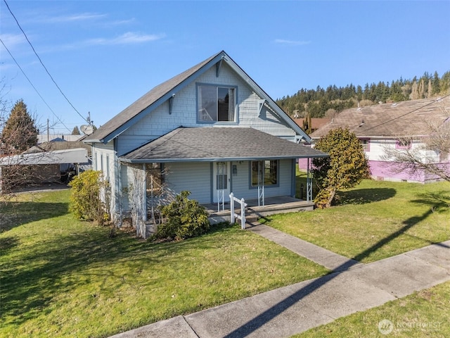 bungalow-style home featuring covered porch, a shingled roof, and a front yard