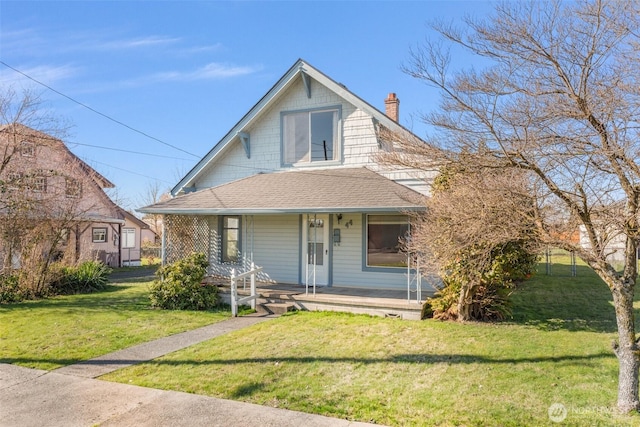 view of front of property with a chimney, a front lawn, a porch, and roof with shingles