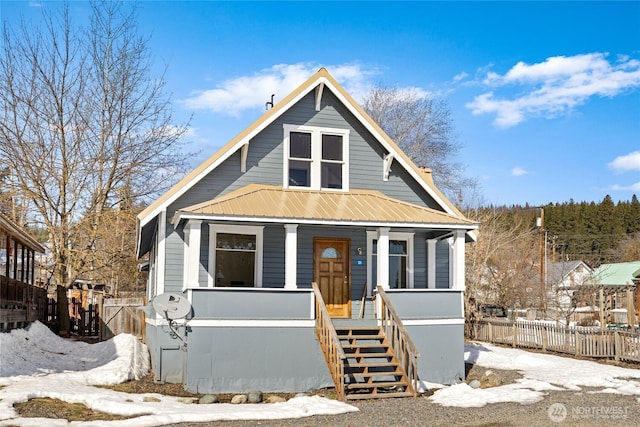 view of front of house featuring covered porch, stairway, fence, and metal roof