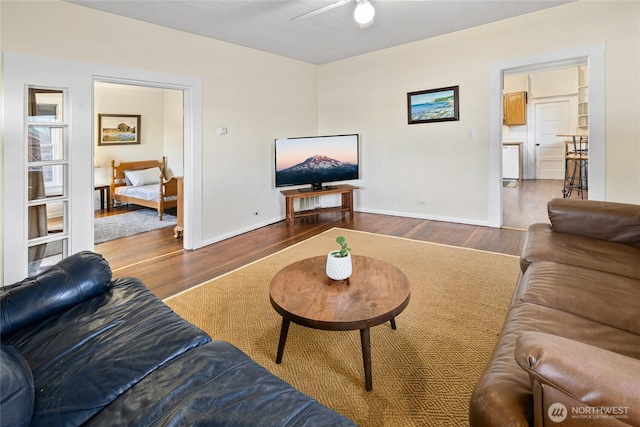 living room featuring ceiling fan, baseboards, and wood finished floors