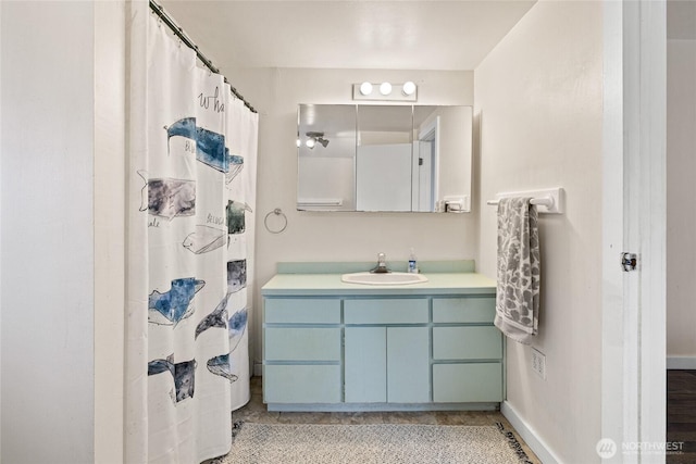 bathroom featuring curtained shower, vanity, and baseboards