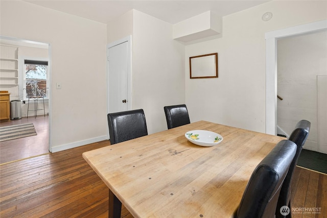 dining space with dark wood-style flooring and baseboards