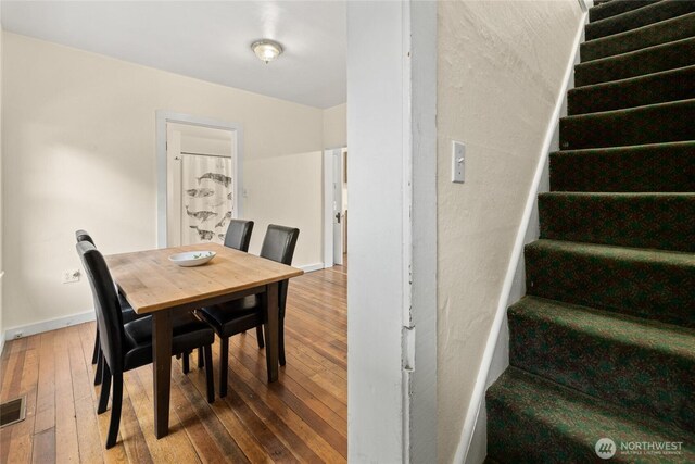 dining space with stairs, hardwood / wood-style floors, and baseboards