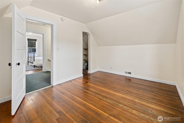 additional living space featuring lofted ceiling, wood-type flooring, visible vents, and baseboards