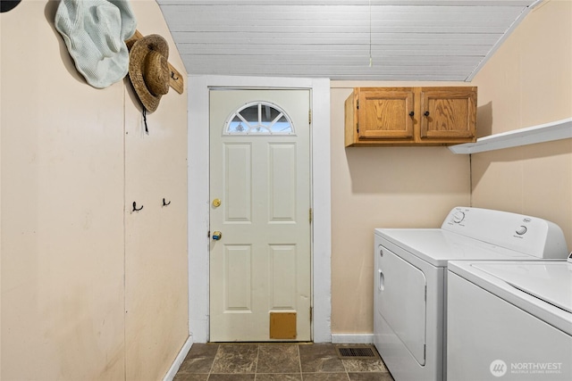 washroom with baseboards, cabinet space, and washer and dryer