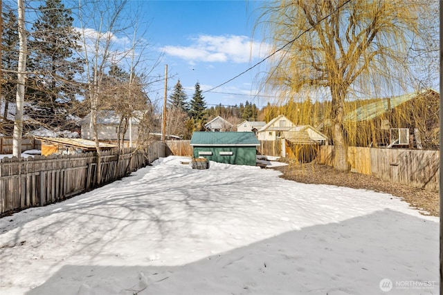 yard covered in snow with a fenced backyard and an outdoor structure