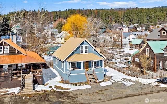 view of front of property with a residential view, metal roof, stairway, and a view of trees