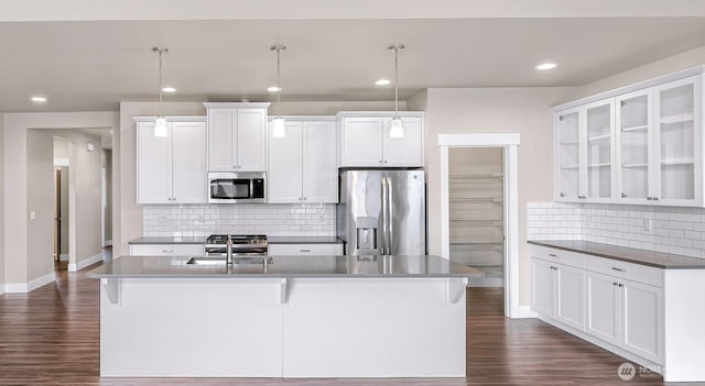 kitchen featuring dark wood finished floors, white cabinets, an island with sink, stainless steel appliances, and a sink