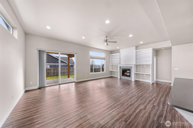 unfurnished living room with recessed lighting, baseboards, dark wood-style flooring, and a stone fireplace