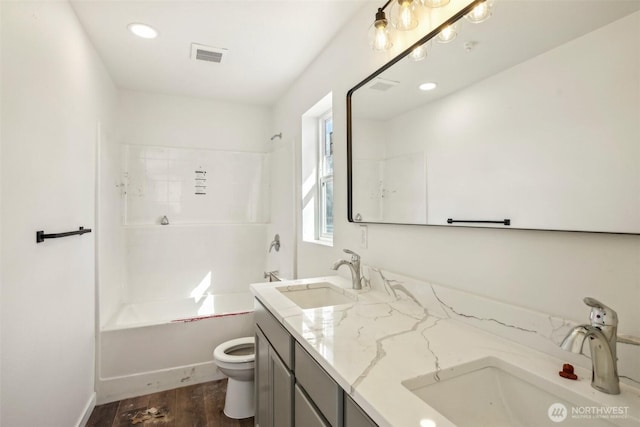 bathroom featuring toilet, wood finished floors, visible vents, and a sink