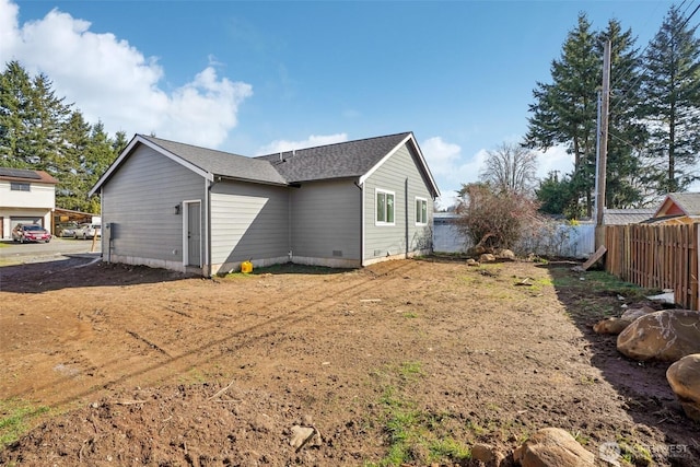 back of property featuring crawl space, roof with shingles, and fence