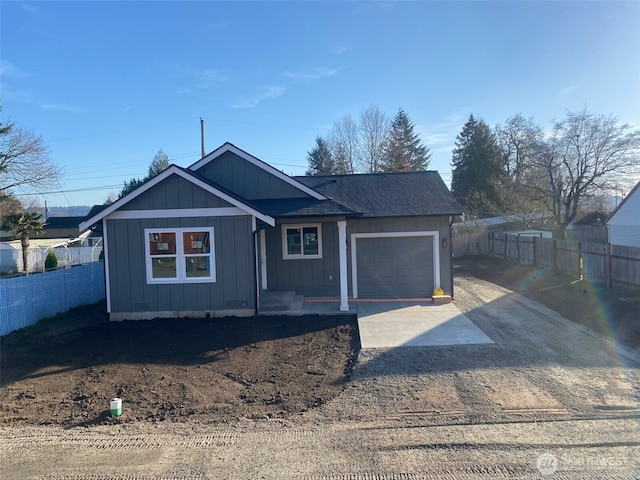 view of front of property featuring fence, board and batten siding, concrete driveway, an attached garage, and a shingled roof