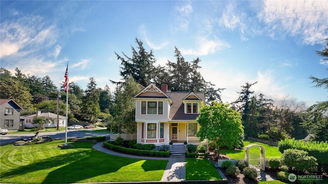 victorian home featuring covered porch, a front yard, and fence