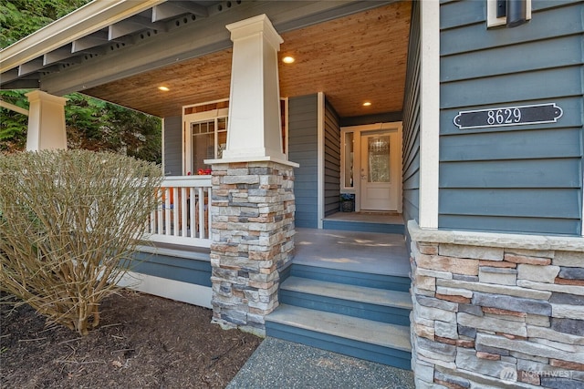 entrance to property featuring stone siding and a porch