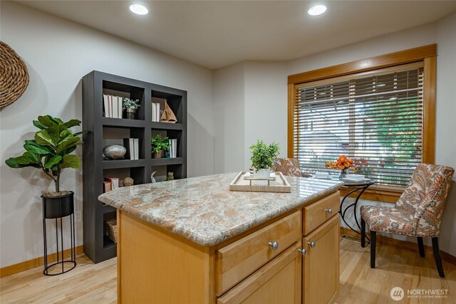 kitchen with recessed lighting, light wood-type flooring, a kitchen island, and light stone countertops