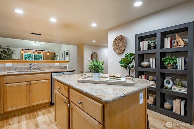 kitchen with light wood finished floors, dishwasher, a center island, a sink, and recessed lighting