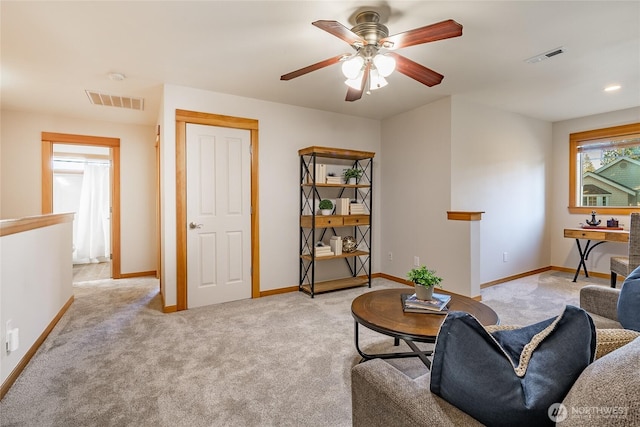 living room featuring visible vents, baseboards, ceiling fan, and light colored carpet