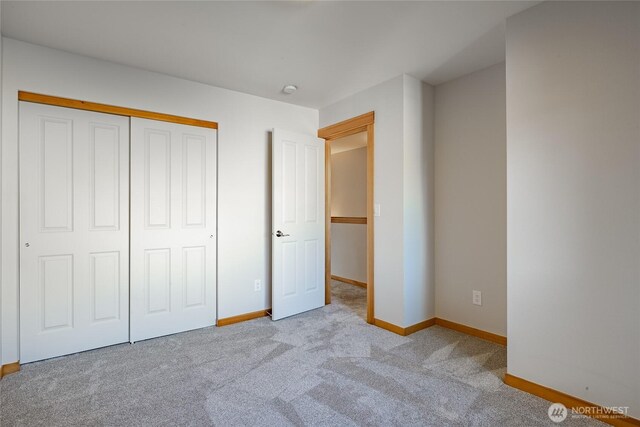 unfurnished bedroom with carpet floors, baseboards, and a closet