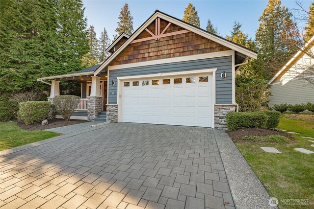 craftsman-style house with a garage, stone siding, a porch, and decorative driveway