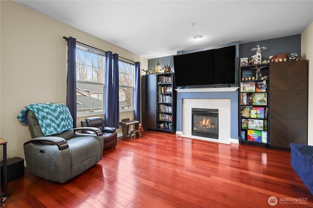 interior space with a tile fireplace and wood finished floors