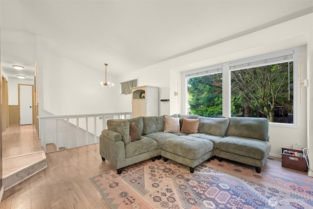 living area with a chandelier, wood finished floors, and vaulted ceiling