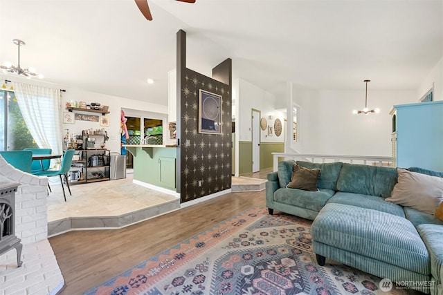 living area featuring ceiling fan with notable chandelier, vaulted ceiling, and wood finished floors