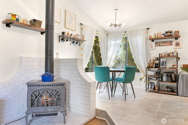 dining area with an inviting chandelier, a wood stove, and lofted ceiling