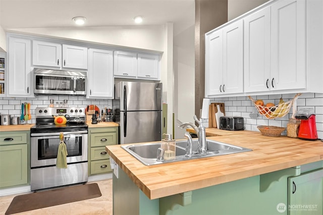 kitchen with green cabinetry, appliances with stainless steel finishes, butcher block counters, and a sink