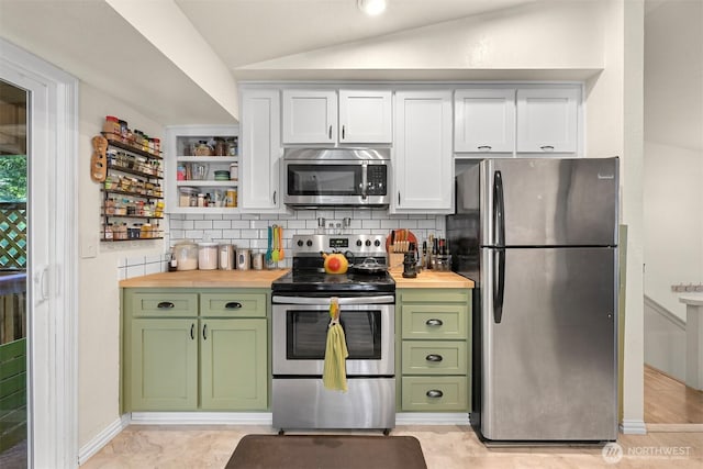 kitchen featuring wooden counters, vaulted ceiling, decorative backsplash, appliances with stainless steel finishes, and green cabinetry