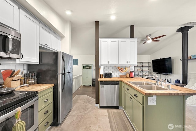 kitchen with wooden counters, a peninsula, a sink, appliances with stainless steel finishes, and green cabinets