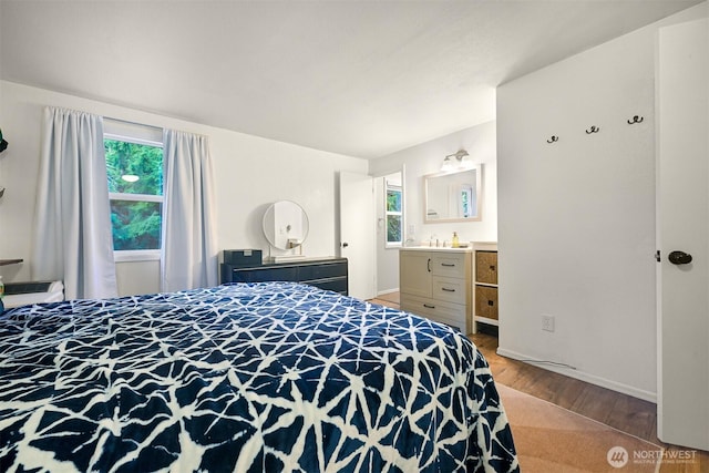 bedroom with baseboards, light wood-style flooring, and ensuite bathroom