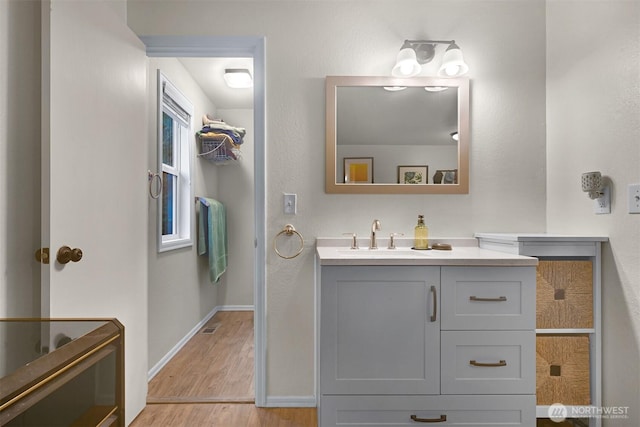 bathroom featuring vanity, wood finished floors, and baseboards