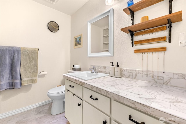 bathroom with vanity, toilet, and baseboards