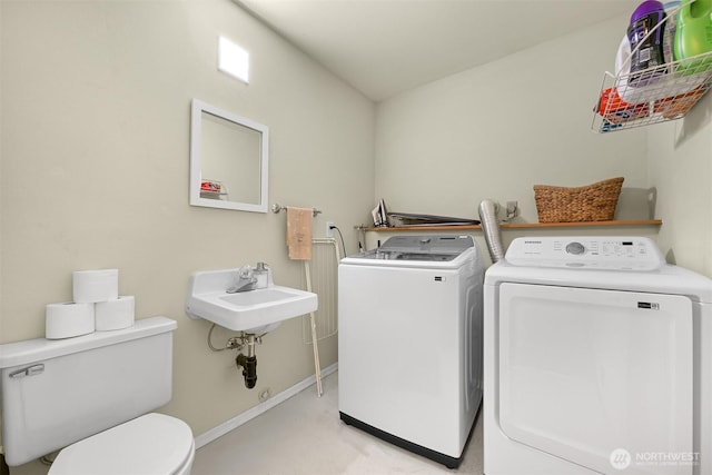 washroom featuring a sink, baseboards, independent washer and dryer, and laundry area