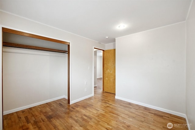 unfurnished bedroom with light wood-type flooring, baseboards, and a closet