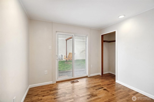 unfurnished bedroom featuring access to exterior, visible vents, baseboards, and wood finished floors