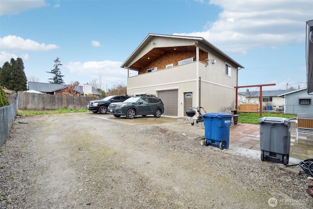 view of home's exterior featuring an attached garage, driveway, and fence