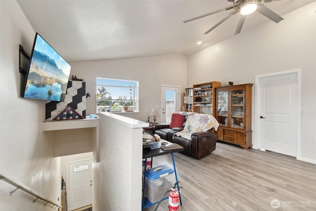 living room with light wood-style flooring, a ceiling fan, and vaulted ceiling