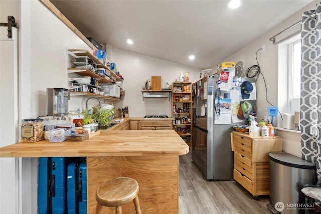 kitchen with light wood-style flooring, wood counters, a barn door, and open shelves