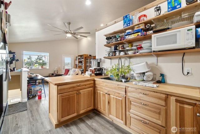 kitchen with lofted ceiling, light wood-style flooring, white microwave, and wood counters