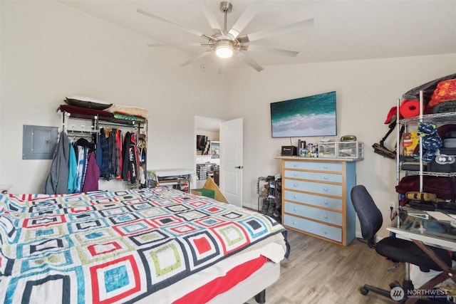 bedroom featuring a ceiling fan, electric panel, wood finished floors, a closet, and vaulted ceiling