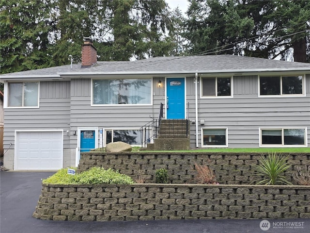 view of front of house with a garage, entry steps, driveway, and a chimney