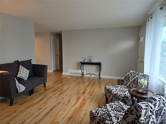 sitting room with light wood finished floors, baseboards, and visible vents