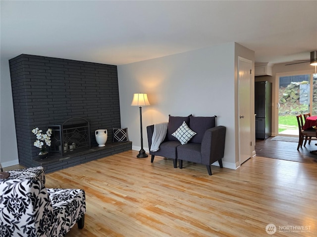 living room featuring light wood finished floors, a fireplace, and baseboards