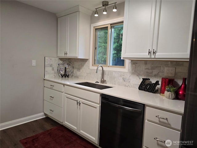 kitchen with tasteful backsplash, dishwashing machine, dark wood-type flooring, light countertops, and a sink