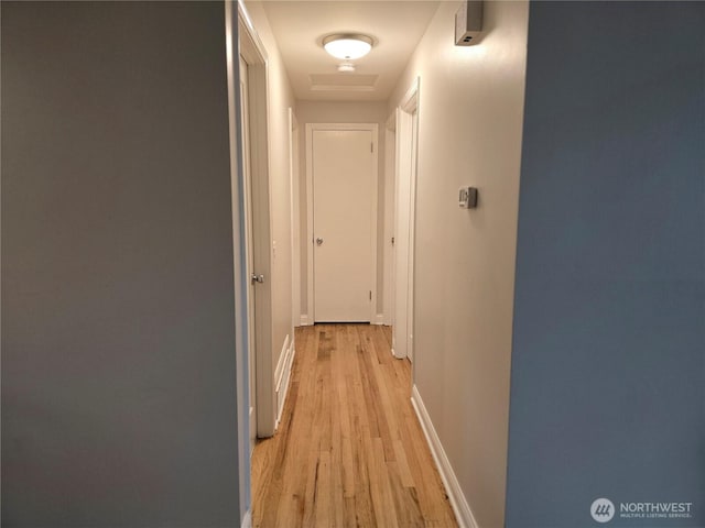 corridor with attic access, baseboards, and light wood-style flooring