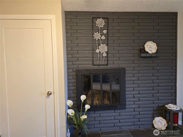 interior details featuring a textured ceiling and a brick fireplace