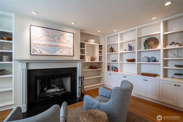 living area with a fireplace with flush hearth, light wood-style floors, and recessed lighting